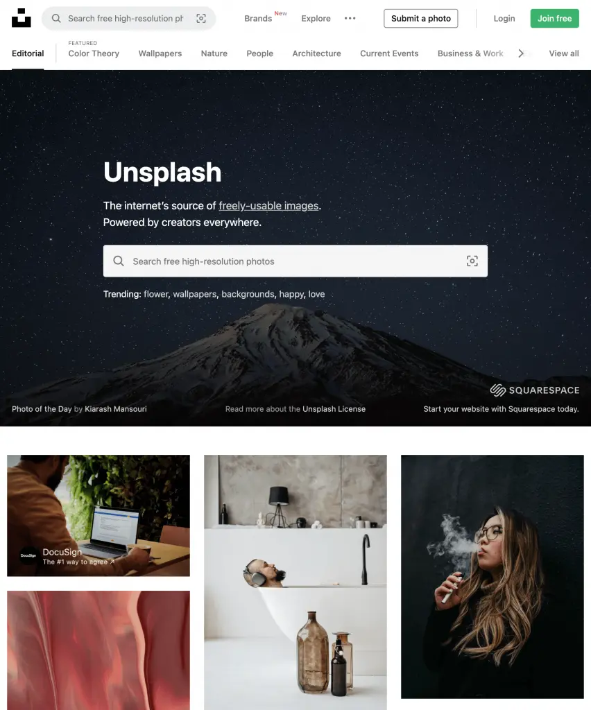 Page d'accueil du site Unsplash avec une barre de recherche de photos haute résolution, un fond de montagnes sous un ciel étoilé et des images miniatures de personnes et d'objets.